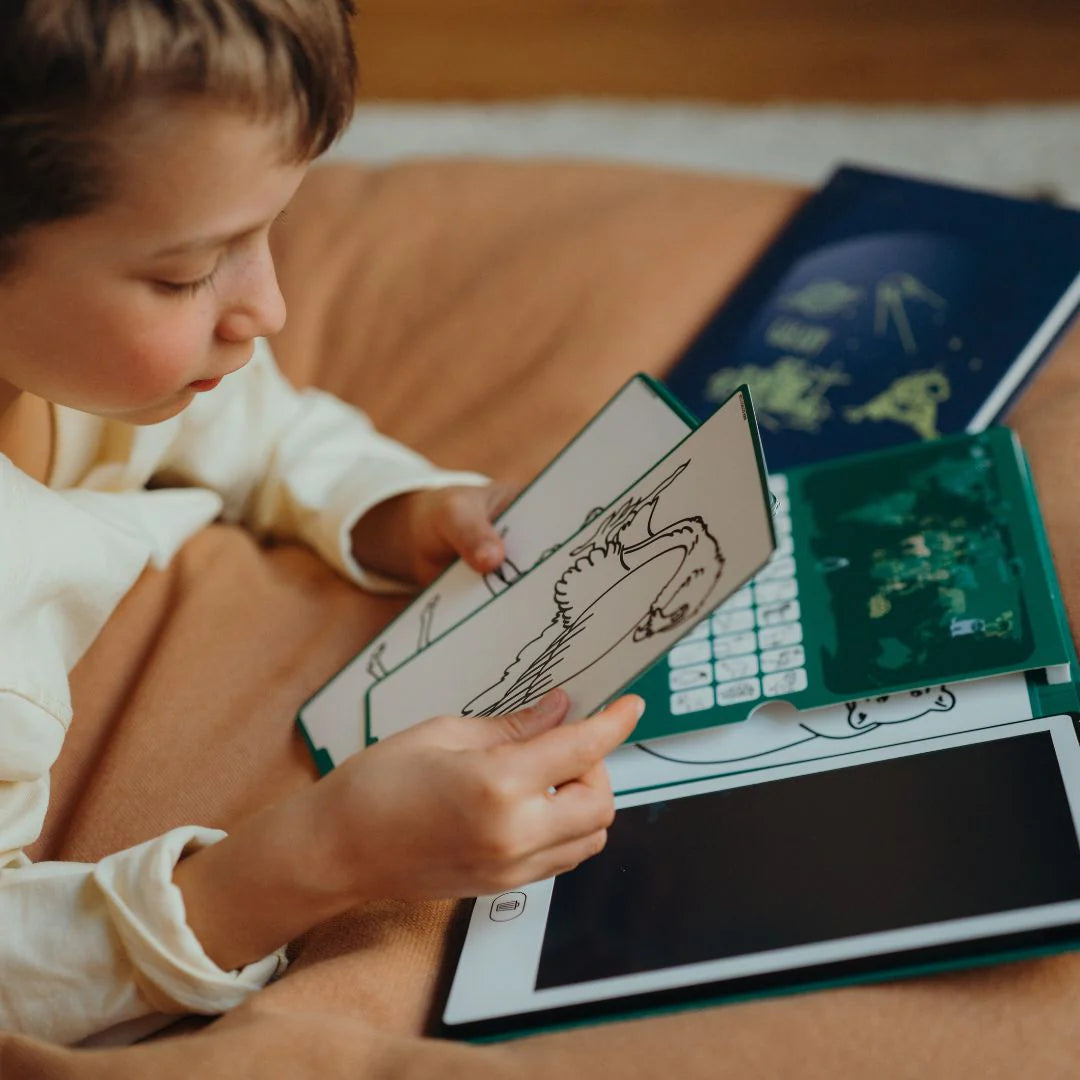 Kidywolf piešimo planšetė – vaikas, piešiantis ant planšetės, laikantis piešimo lapą, patogioje aplinkoje.