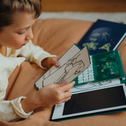 Kidywolf piešimo planšetė – vaikas, piešiantis ant planšetės, laikantis piešimo lapą, patogioje aplinkoje.