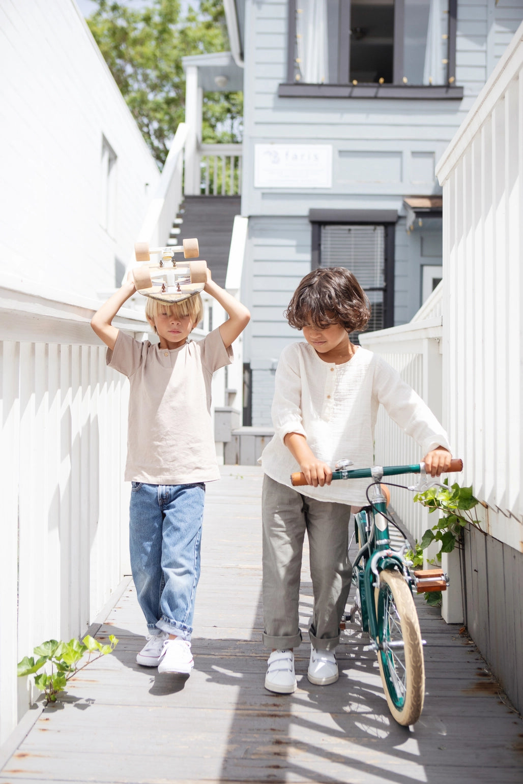 Du vaikai lauke: vienas neša lentas ant galvos, kitas stumia Banwood 16 klasikinis vintažinis dviratis.