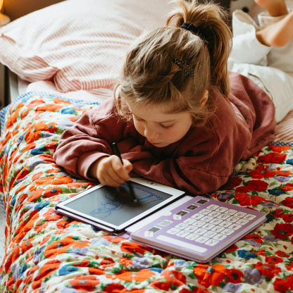 Vaikas piešia ant Kidywolf piešimo planšetės - PRINCESSES ant lovos su spalvingu patalynės užvalkalu.